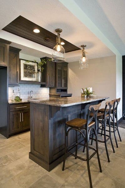 Modern basement bar with dark wood cabinets, marble countertop, and pendant lighting.