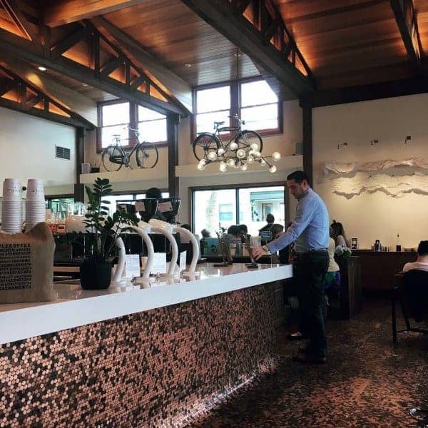 Cafe with penny tile bar counter, high ceilings, and rustic-modern decor featuring bicycles.