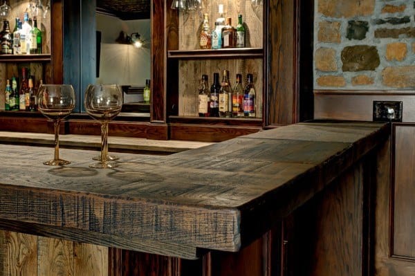 Rustic wooden bar top with textured wood design and storage shelves in the background.