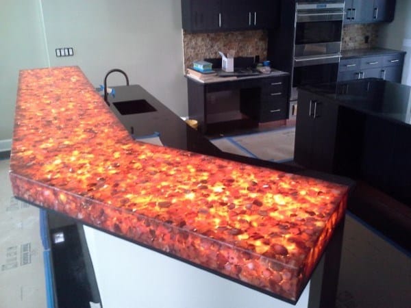 Illuminated bar top with a glowing resin design featuring warm colors in a modern kitchen setting.