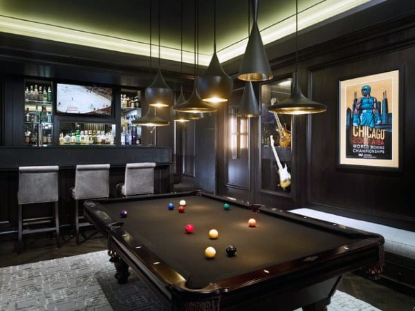 A stylish game room with a pool table, bar, and modern pendant lights featuring a Chicago poster adorning the wall