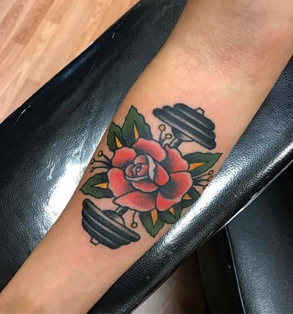 Traditional-style tattoo of a red rose with a barbell through it, blending strength and beauty in a bold, colorful design.