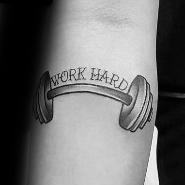 Barbell tattoo with the words “Work Hard” curved along the bar, symbolizing discipline, effort, and strength in fitness.