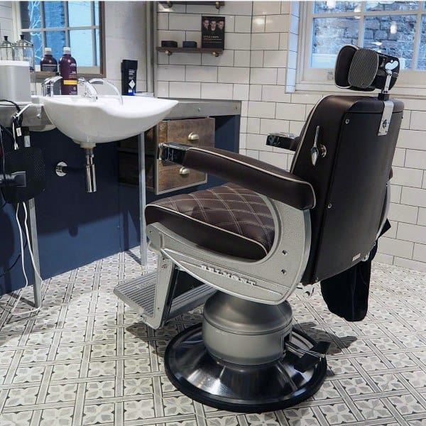 Barbershop with vintage chair, patterned tile flooring, and white tiled walls.