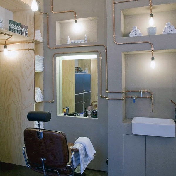 Barbershop with copper piping decor, minimalist shelving, and a vintage leather chair.