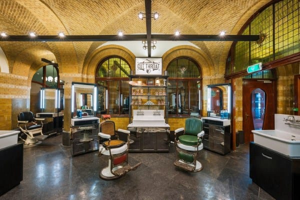 Spacious Victorian barbershop with vintage chairs, arched windows, and elegant interior design.