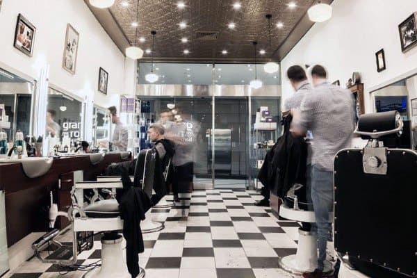 Classic barbershop with checkered floors, vintage chairs, and a modern glass storefront.