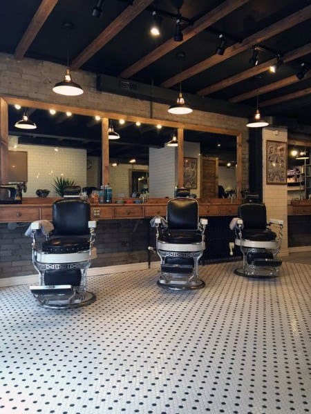 Rustic barbershop with vintage chairs, exposed wooden beams, and patterned tile flooring.