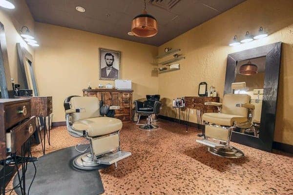 Barbershop with penny tile flooring, vintage barber chairs, and warm lighting.