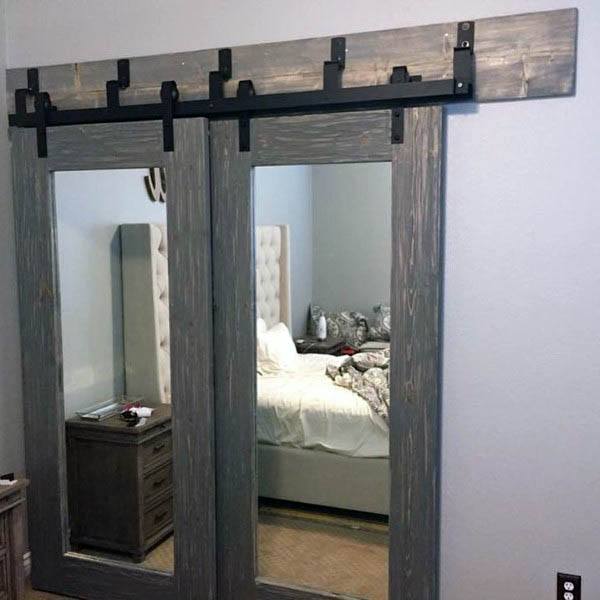 A rustic barn-style closet door with mirrors framed in weathered wood, adding a stylish touch to the bedroom