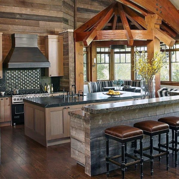 Rustic kitchen with barn wood island, exposed beams, modern appliances, and bar stools.