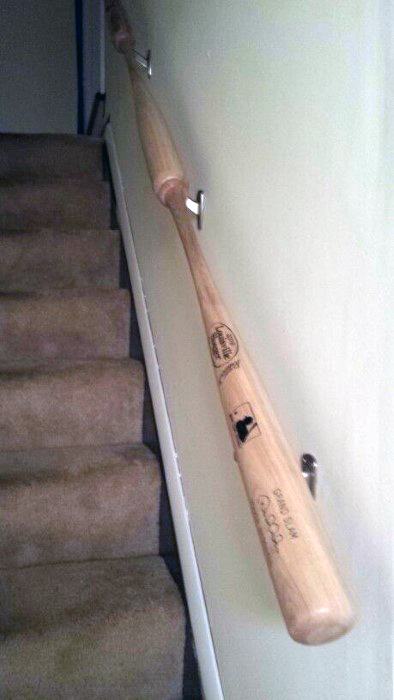 A staircase with a wooden baseball bat used as a handrail