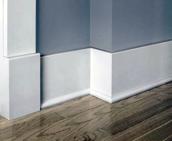 White baseboard molding with gray walls and light hardwood flooring.