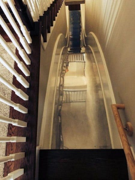 Creative indoor slide design installed next to a staircase, offering a fun and unique way to descend to the lower floor.