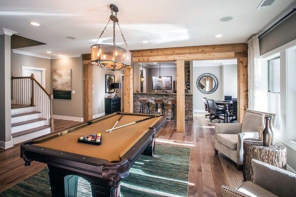 Farmhouse billiard room with a wooden pool table, cozy seating, and exposed wood beams.