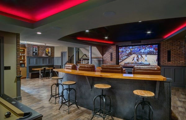 Home theater with a large screen showing a basketball game, bar seating, and a modern industrial design