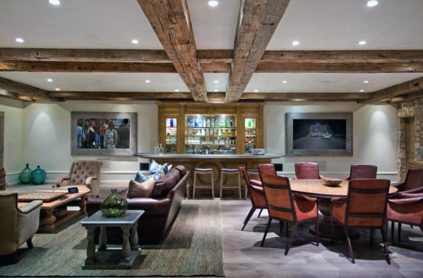 Cozy man cave with exposed wooden beams, leather sofas, a bar, and a dining table with chairs