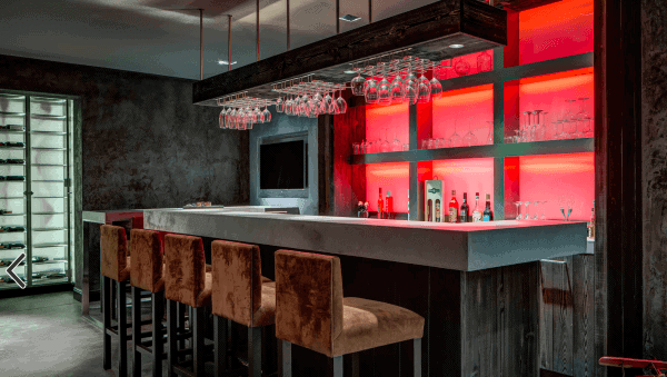 Sleek modern bar with a stylish countertop, illuminated shelving, and plush seating in warm tones.