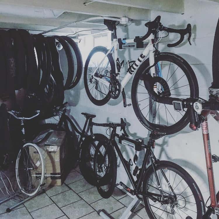 Basement with hanging road bikes and spare tires organized on racks for bike storage.