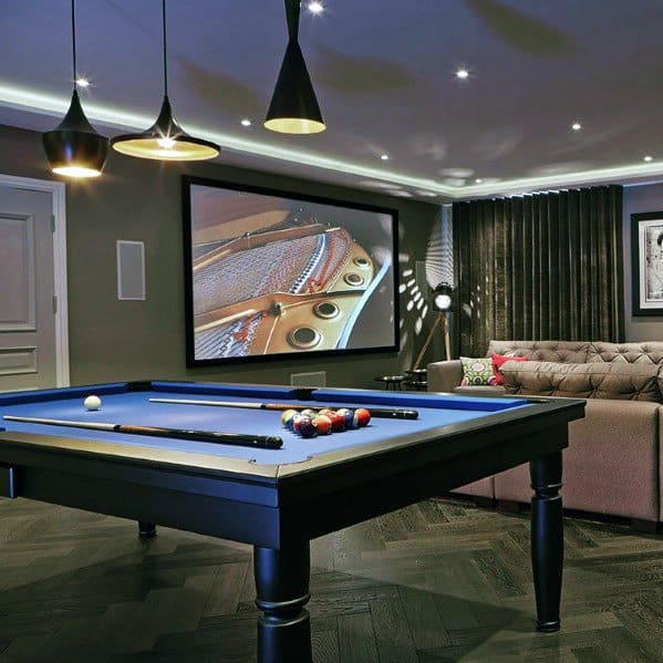 Eclectic billiard room with blue pool table, home theater screen, and modern pendant lighting.