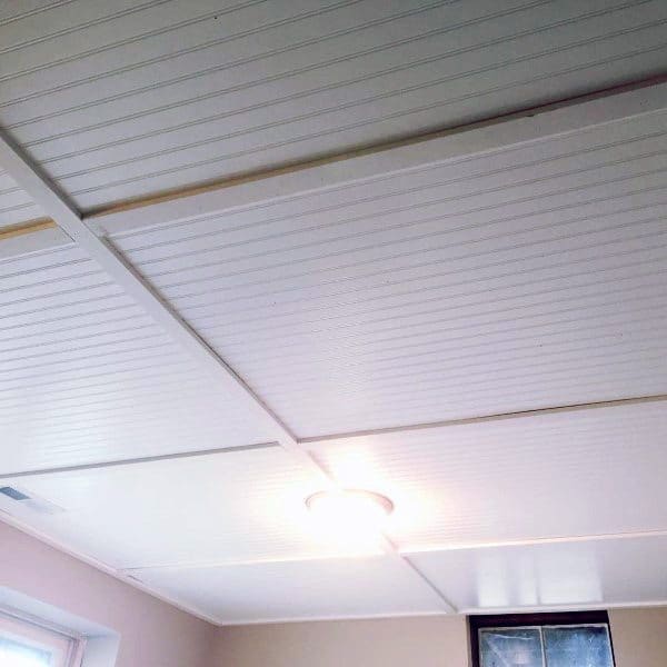 White shiplap ceiling with recessed lighting in a modern basement.