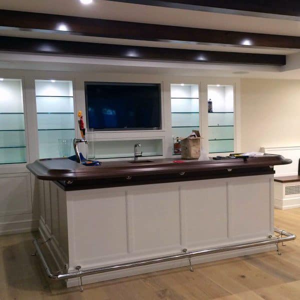 Stylish basement bar with exposed dark wooden beams and illuminated glass shelving.
