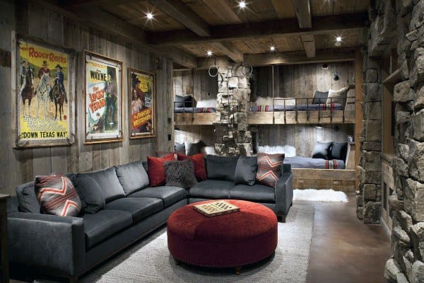Rustic basement with wooden beams, bunk beds, stone accents, sectional sofa, and vintage posters.