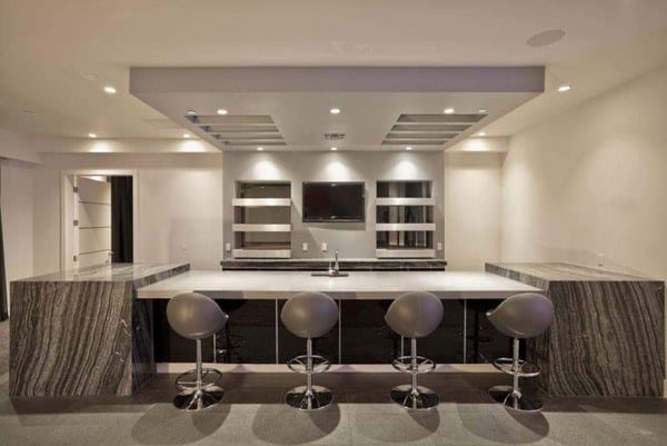 Modern basement bar with marble countertops, sleek stools, and recessed lighting.