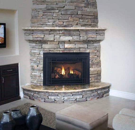 Stone corner fireplace with built-in shelves, marble mantel, and cozy seating arrangement.