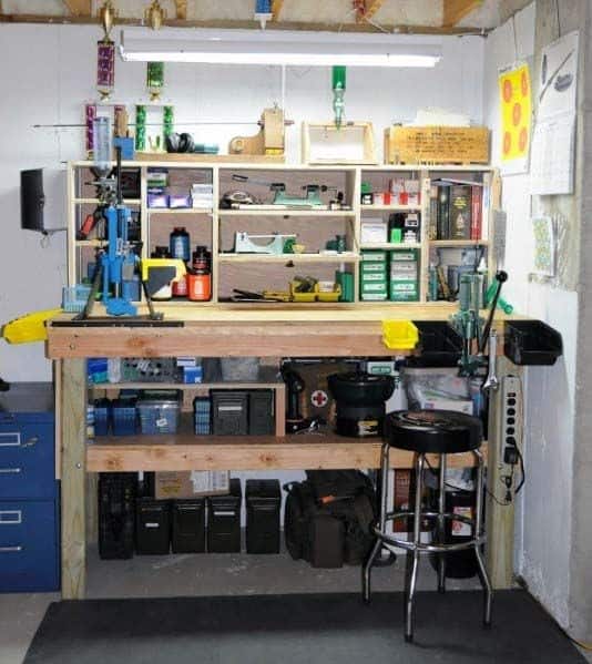 Well-lit reloading bench setup with shelving for tools, supplies, and presses, organized for efficient workspace use