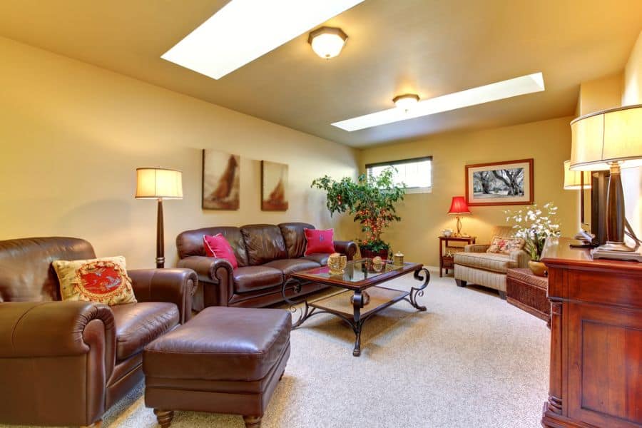 country style basement living room brown leather couches glass top table ottoman