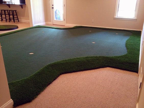 Indoor mini-golf area with artificial grass and several holes located in a carpeted room