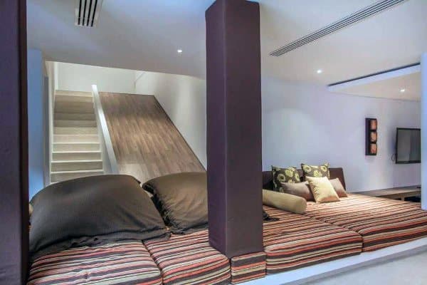 Cozy lounge area with striped cushions and pillows, plus a modern staircase slide in the background