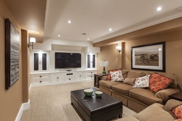 Cozy basement living room with sectional sofa, wall sconces, and recessed lighting surrounding a TV unit.