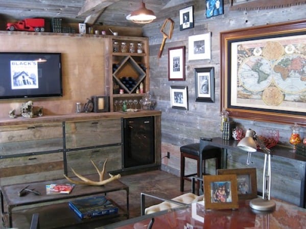 Rustic man cave with wood paneling, vintage decor, books, map wall art, and a small bar area