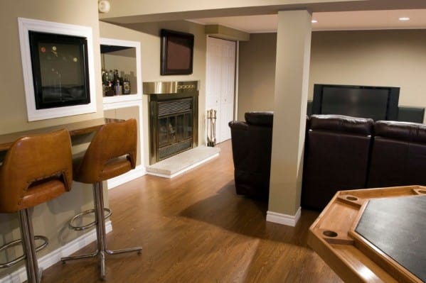 Cozy man cave with bar stools, fireplace, leather sofa, and TV, pool table sits prominently in the foreground