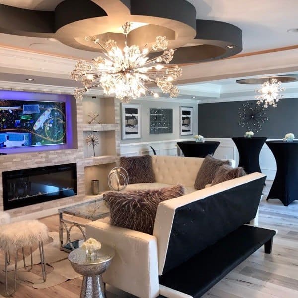Luxurious basement lounge with modern crystal chandeliers, fireplace, and elegant seating area.