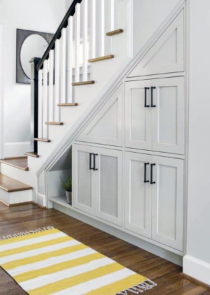 White staircase with under-the-stairs storage cabinets and wooden steps in a modern home interior.