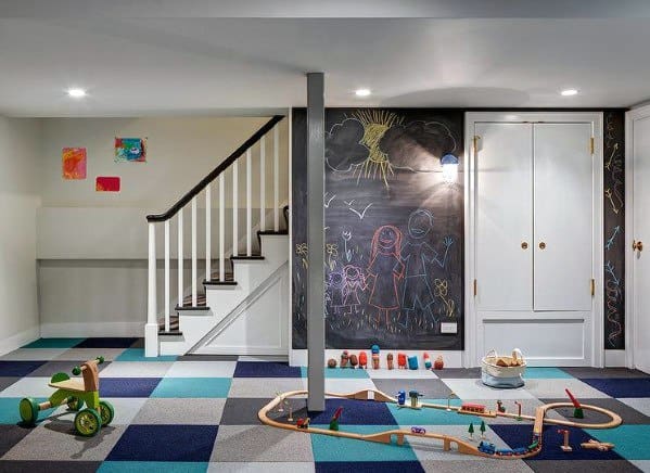 Basement playroom with colorful flooring, a staircase featuring white vertical railing, and a chalkboard wall.