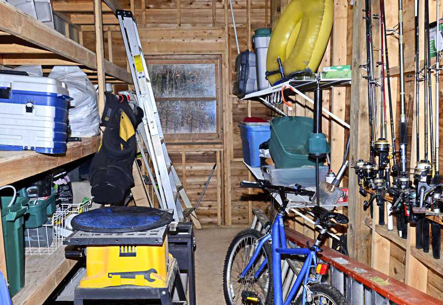 Basement storage with fishing rods, tools, a bicycle, ladder, and various gear on shelves.