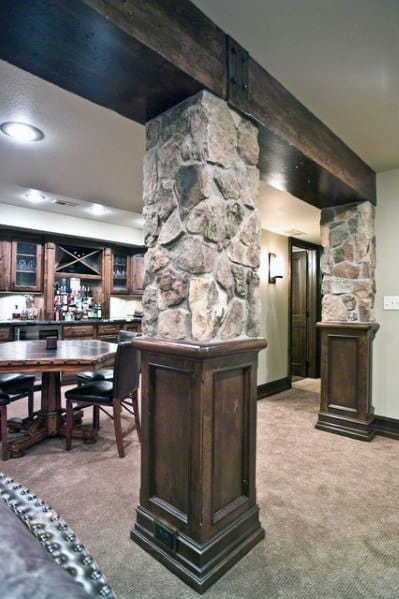 Basement with stone and wood support poles, built-in bar, and rustic dining area.
