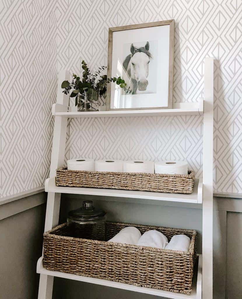 White ladder shelf with wicker baskets holding towels, toilet paper, and a glass jar.