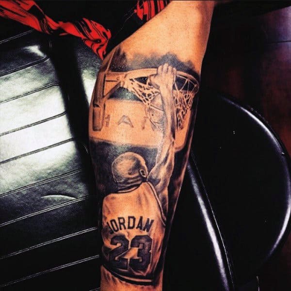 Tattoo of a basketball player with "Jordan" and the number 23 dunking a ball on an arm