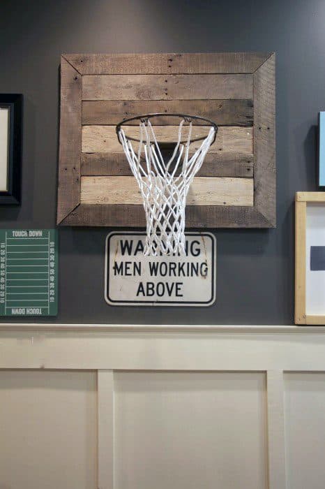 Basketball hoop mounted on a wall with a "Men Working Above" sign underneath