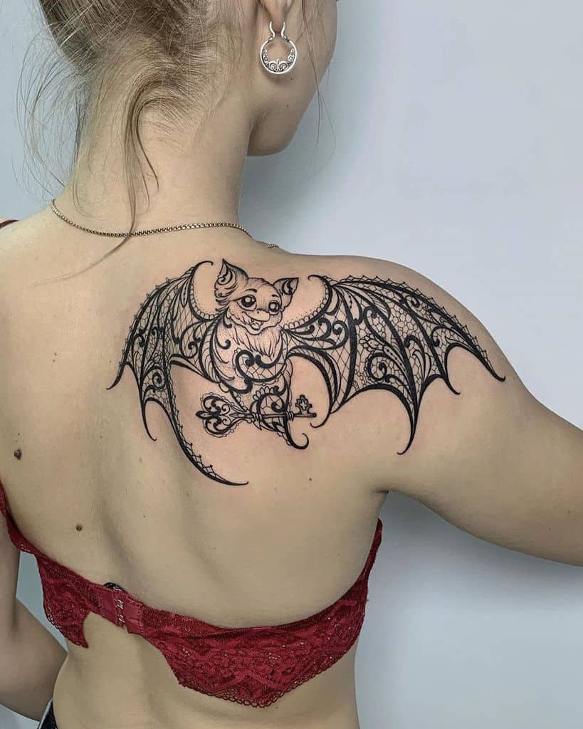 Elegant bat tattoo on the upper back with intricate lace and filigree patterns, blending gothic and decorative elements.