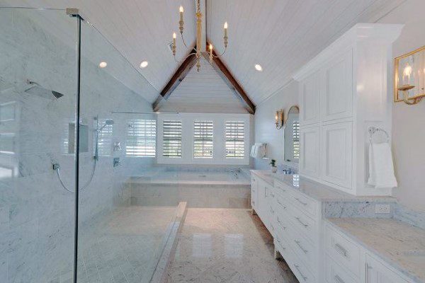 Elegant bathroom with vaulted shiplap ceiling, exposed beams, walk-in shower, and white cabinetry.