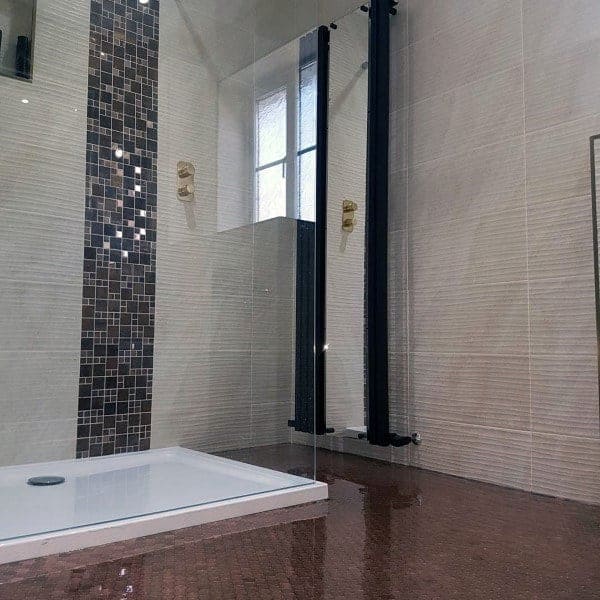 Modern bathroom with glossy epoxy penny tile floor, mosaic wall accent, and glass shower enclosure.