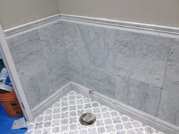 Bathroom with gray marble wainscoting and white and gray floral-patterned floor tiles.