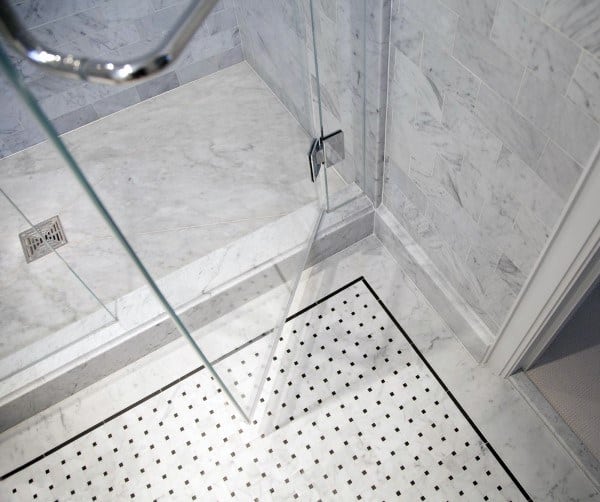 Bathroom with white marble tiles, black border detail, and a glass shower enclosure.