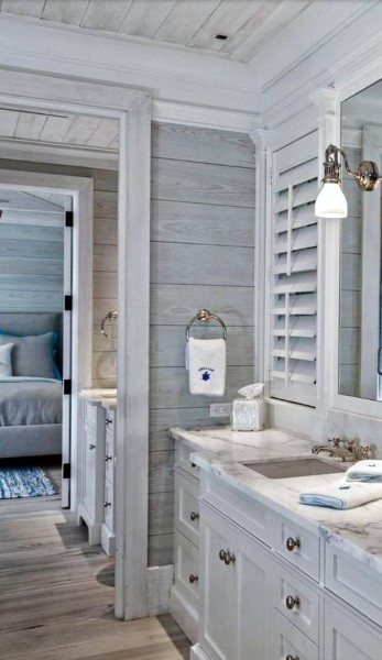 Farmhouse-style bathroom with shiplap walls, marble countertop, and shuttered window.